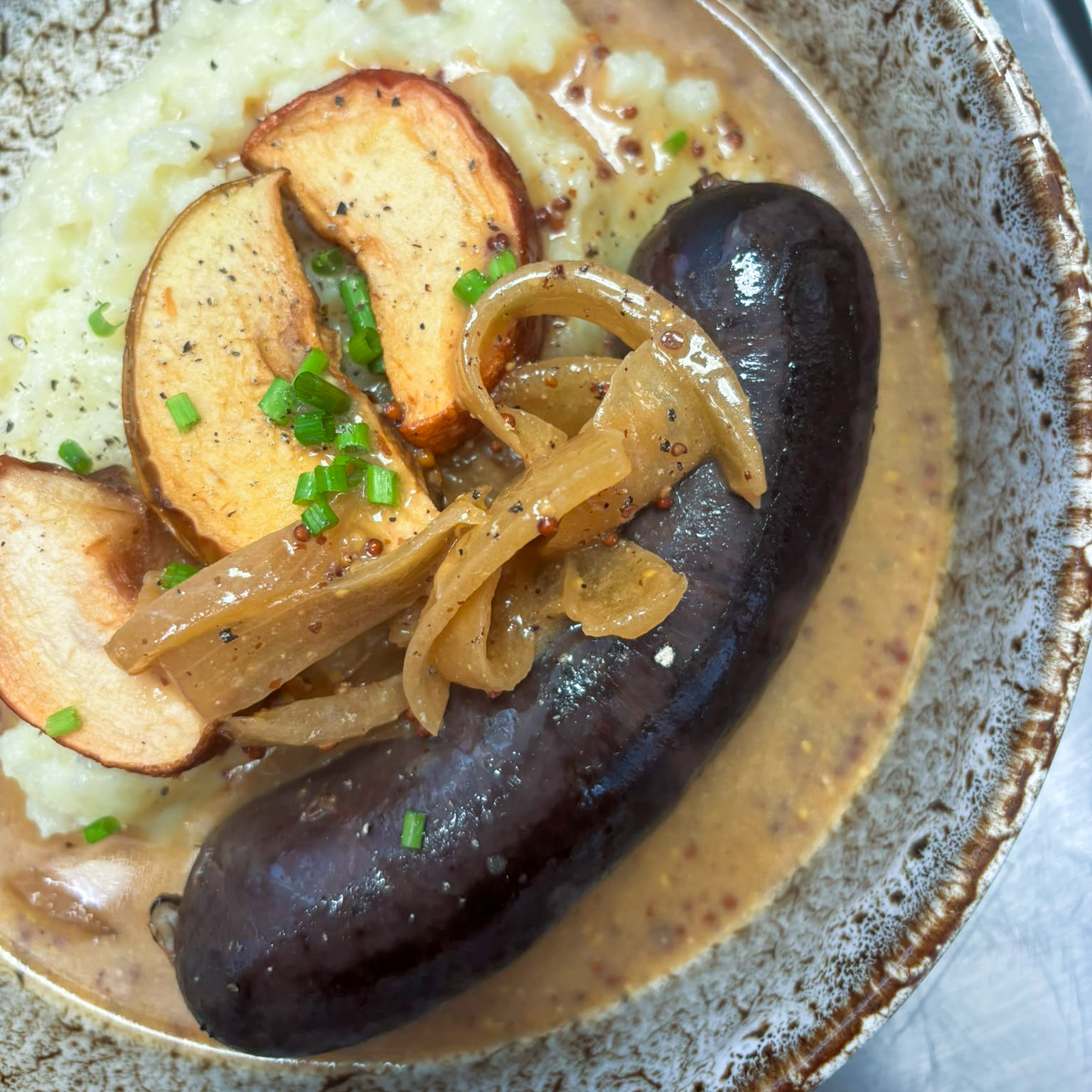 Boudin noir à l’ancienne aux oignons, mousseline de pommes de terre, pommes BIO rôties et sauce au cidre et moutarde en grains